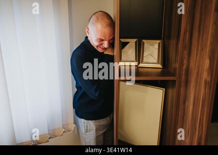 Ein schüchterner Mann lacht neben Bücherregalen während eines zwanglosen Geschäftsteams in einem modernen Büroinnenraum Stockfoto