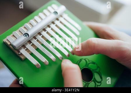 Nahaufnahme von Händen, die eine grüne Kalimba spielen, eine moderne Version des afrikanischen Mmbira-Instruments, auch bekannt als Daumenklavier, die beruhigende Melodien erzeugt Stockfoto