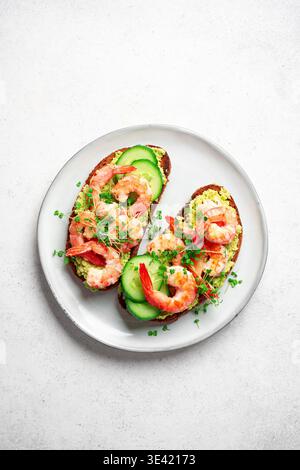 Avocado Shrimp Sandwiches für gesundes Low Carb Frühstück. Toasts mit gegrillten Garnelen, pürierter Avocado und Mikrogrün auf weißem Hintergrund, Top V Stockfoto