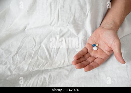 Zwei Pillen und Kapsel in der Hand auf weißem Hintergrund, Draufsicht. Senior Mann, der Medikamente nimmt, Medikamente in der Hand hält. Tägliche Ergänzungen oder se Stockfoto