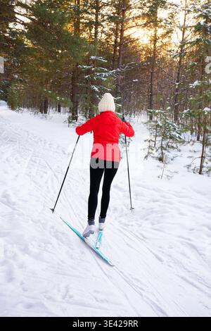 Frau auf Skilanglauf im Winterwald, Rückansicht. Gesunder Lebensstil, Outdoor-Aktivitäten und winterliches Fitnesskonzept. Aktive Menschen, Skifahren com Stockfoto
