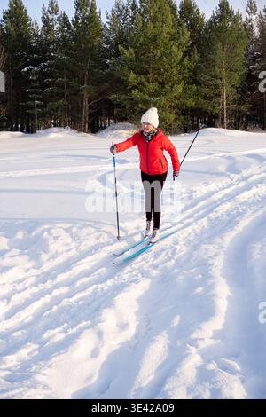 Frau auf Langlauf im sonnigen Winterwald. Gesunder Lebensstil, Outdoor-Aktivitäten und winterliches Fitnesskonzept. Aktive Personen. Stockfoto