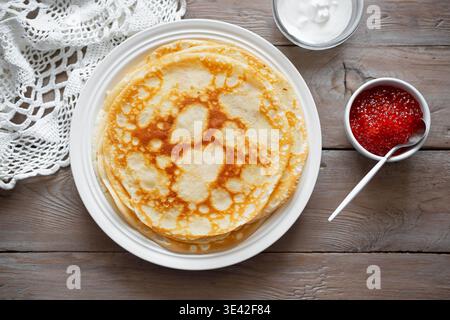 Hausgemachte, dünne Crepes mit rotem Kaviar und Creme. Herzhafte Pfannkuchen mit Lachsfischkaviar. Maslenitsa Karneval. Stockfoto