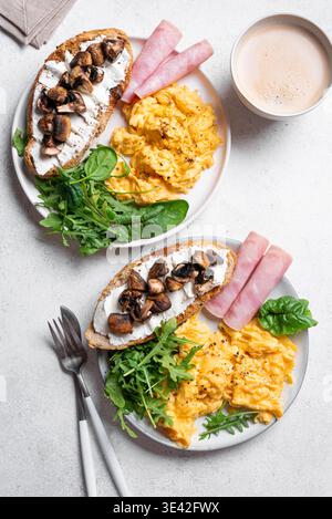 Gesunde, ausgewogene Frühstücksteller. Rührei, Gemüse, Schinken, Sandwich mit Frischkäse und gebratenen Pilzen. Frühstück für zwei Personen, Panoramablick. Stockfoto