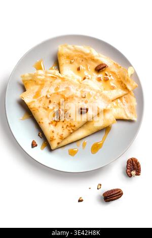 Crepes Suzette mit Honig und Pekannüssen isoliert auf weißem Hintergrund. Köstliche hausgemachte Crepes auf Teller zum Frühstück. Stockfoto