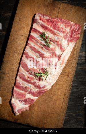 Rohe Schweinerippchen auf rustikalem hölzernem Schneidebrett, fertig zum Kochen. Schweinesparerib. Stockfoto