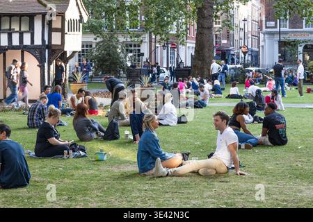 Menschen, die sich auf dem Gras in einem Stadtpark entspannen. London, UK, 23. Juli 2023 Stockfoto