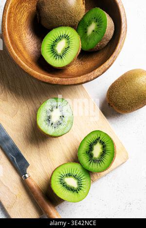 Kiwi-Früchte in Holzschale. Ganze Früchte und halbe Stücke grüne Kiwi sind nah dran. Frisch reife Kiwi. Bio gesunde Ernährung. Stockfoto