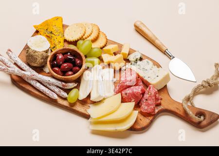 Antipasti auf einem Holzbrett mit verschiedenen Käsesorten, Wurstwaren, Oliven und Trauben Stockfoto
