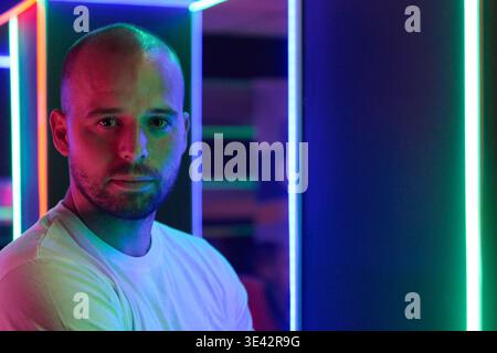 Neon-Porträt eines selbstbewussten Mannes in farbenfrohen LED Lights Studio mit Kinoatmosphäre Stockfoto