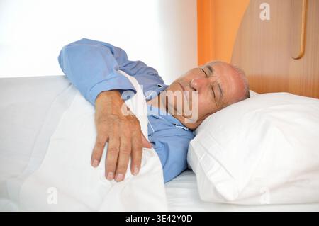 Porträt eines älteren Mannes, der im Bett ruht, während er träumt Stockfoto