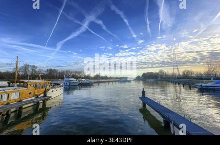 Eine ruhige und ruhige Yachthafenszene in der Morgenröte mit Booten, ihren Reflexionen und einem atemberaubenden Himmel Stockfoto