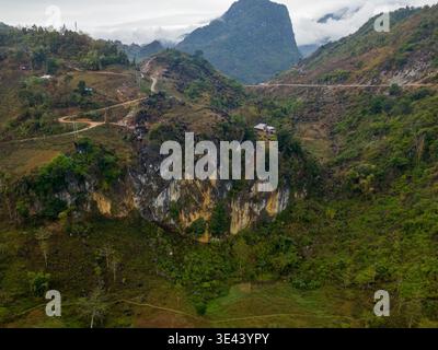 Pja Pass in der Nähe von mir, Vietnam – 13. Januar 2024: Ein Blick auf die Drohne zeigt eine gewundene Bergstraße über felsigen Klippen und ein ländliches Tal im Norden Vietnams. Stockfoto