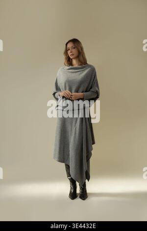 Studio-Porträt des Modells in grauem, gestricktem monochromen Outfit mit asymmetrischem Midirock Stockfoto