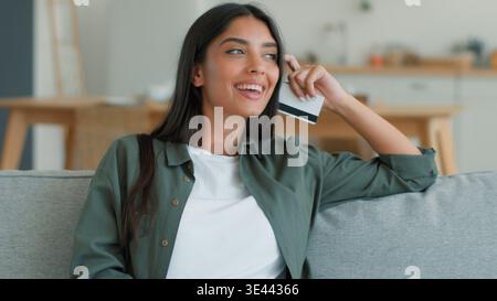 Glückliche fröhliche indische muslimische Frau mit Handy Online-Shopping zu Hause Couch Küche bestellen Essen Lieferung Eingabe Kreditkarte Arabian Stockfoto
