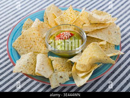 Nachos mit Guacamole auf blauer Platte Stockfoto