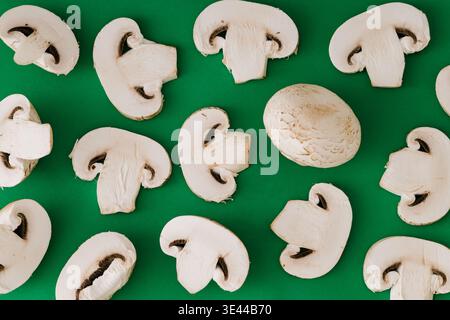 Champignon-Pilzmuster auf grünem Hintergrund. Lebensmittelkonzept. Frisch geschnittene Pilze flach legen. Stockfoto