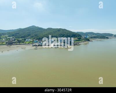 Aus der Vogelperspektive sehen Sie Ganghwados weite Wattgebiete bei Ebbe und sehen komplizierte Gezeitenkanäle, Seonsu Port und Seokmodo Island unter einem klaren blauen Himmel. Stockfoto