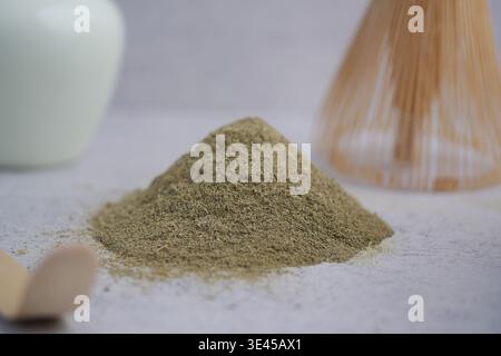 Matcha-Pulver sitzt auf einer Oberfläche mit Teewerkzeugen in der Nähe Stockfoto