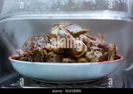 Gedämpfte Lammkäfer in weißer Schüssel unter Glasdeckel, chinesische Küche, Peking Stockfoto