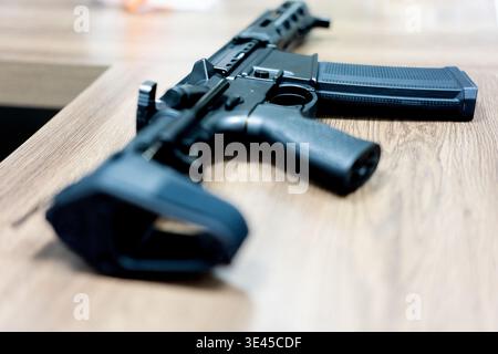 Schwarzes Gewehr im Stil AR-15 auf Holztisch im Innenbereich, USA Stockfoto