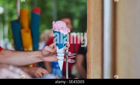 Ein Eisverkäufer schöpft Eis in bunte Waffelkegel. Stockfoto