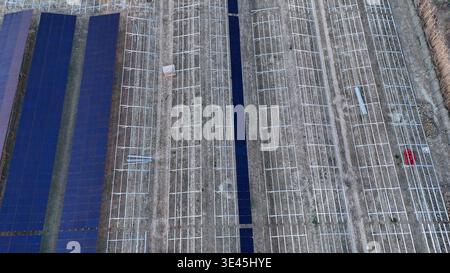 Großer zukünftiger Solarpark im Bau, mit mehreren Reihen von bereits installierten dunkelblauen Photovoltaikpaneelen und riesigen Bereichen aus Metallrahmen Stockfoto
