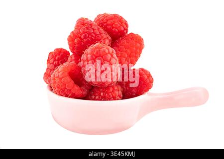 Frische rote Himbeeren in einer kleinen rosafarbenen Keramikschale mit Griff auf weißem Hintergrund, isoliert mit Schnittpfad Stockfoto
