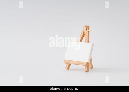 Leere Leinwand auf hölzerner Staffelei auf weißem Hintergrund. Minimales Kunstmodell. Idee zur Branding-Präsentation. Kreativer Kopierbereich. Stockfoto