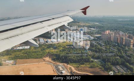 Flugzeugflügel fliegt über Industrie- und Wohngebieten in der Nähe von Moskau Stockfoto
