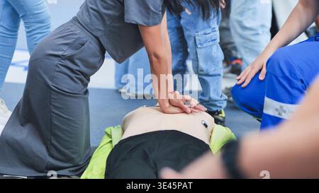 Person, die während des erste-Hilfe-Schulungskurses eine HLW-Thoraxkompression an der Schaufensterpuppe durchführt Stockfoto