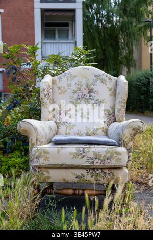 Stuhl mit Blumenmuster, der draußen in der Nähe grüner Pflanzen steht. Hochwertige Fotos Stockfoto
