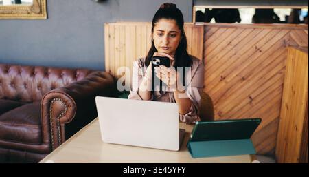 Techniker, Frau und verwirrt mit Telefon im Café wegen schlechter Bewertung, Lagerfehler oder falscher Bestellung. Laptop-, Tablet- und Restaurantbesitzer mit Smartphone für Stockfoto
