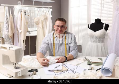 Die Schneiderin näht Hochzeitskleid am weißen Tisch im Atelier Stockfoto