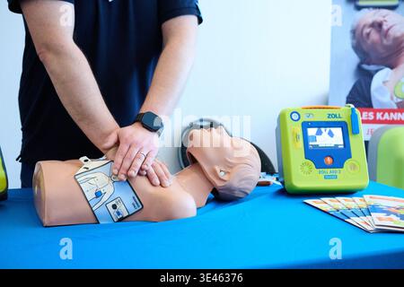 Berlin, Deutschland. März 2026. Ein Mitarbeiter des Zoll Medical AED demonstriert den Schülern der Cosmopolitan School die Reanimation mit einer Reanimationspuppe und demonstriert Thoraxkompressionen, während ein automatisierter externer Defibrillator (AED) auf einem Tisch daneben steht. Das Projekt „Staying Alive“, initiiert von H. Bauckhage, einem Abitur, zielt darauf ab, junge Menschen in Notsituationen richtig zu handeln. Ziel ist es, die Öffentlichkeit für das Thema Wiederbelebung zu sensibilisieren. Annette Riedl/dpa/Alamy Live News Stockfoto