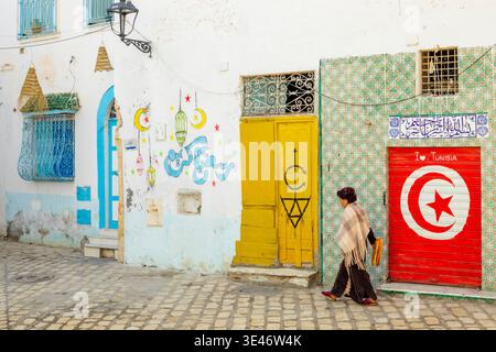 Tunesien, Golf von Hammamet, Sousse, Medina, von der UNESCO zum Weltkulturerbe erklärt, Tunesierin mit Brot vor einer Ladenfront in den Farben der tunesischen Flagge Stockfoto
