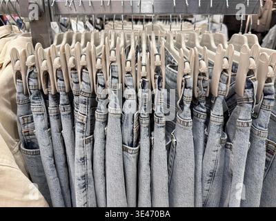 Denim-Jeans an Kleiderbügeln im Einzelhandel mit verschiedenen Styles im Hintergrund. Mobiles Foto Stockfoto