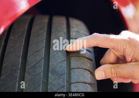 Nahaufnahme eines Mannes, der die Reifenprofiltiefe am Fahrzeug überprüft Stockfoto