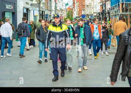 Garda Polizist auf Patrouille in der Grafton Street Dublin zum St. Patricks Day 2026. Irische Strafverfolgungsbehörden in Menschenmengen. Stockfoto