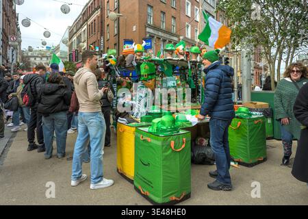 Festliche Atmosphäre auf den Straßen von Dublin, bei der Touristen irische Accessoires für die St. Patrick’s Day Parade kaufen Stockfoto
