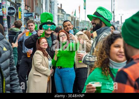 Energie nach der Parade auf den Straßen. Freunde feiern den St. Patrick's Day in Dublin mit grünem Bier und festlichen Outfits für den irischen Nationalurlaub Stockfoto