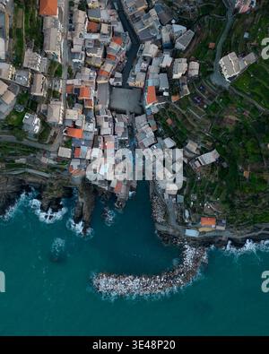 Aus der Vogelperspektive auf die farbenfrohen Häuser und den kleinen Hafen mit einem Steinbruch in Riomaggiore, Ligurien, Italien. Stockfoto
