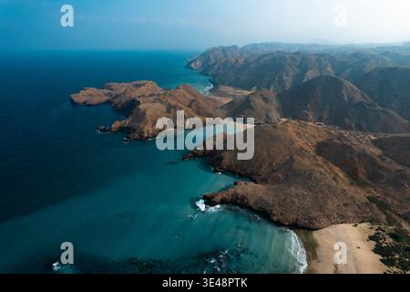 Blick aus der Vogelperspektive auf Sultan Beach mit zerklüfteten felsigen Hügeln und türkisfarbenem Meer Oman. Stockfoto