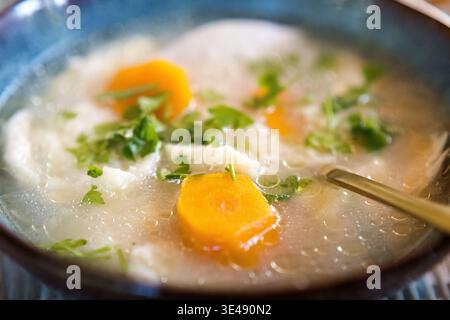 Brühe mit Knödeln, Karotten und Petersilie in einer dekorativen Schüssel. Stockfoto