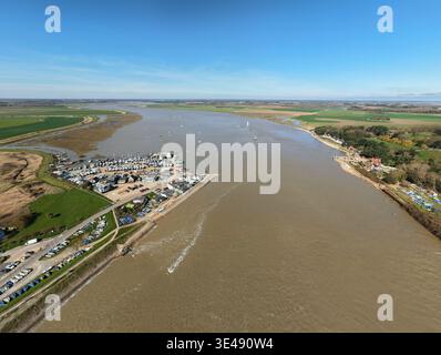Aus der Vogelperspektive auf den schlammigen Fluss Deben, der sich an den grünen Feldern und den malerischen Gebäuden von Felixstowe Ferry, Felixstowe, England, Großbritannien schlängelt. Stockfoto