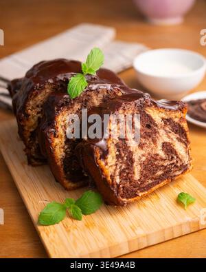 Köstlicher Marmor-Schokoladenkuchen mit glänzender Ganache und frischer Minzgarnitur Stockfoto