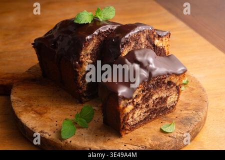 Köstlicher Marmor-Schokoladenkuchen mit glänzender Ganache und frischer Minzgarnitur Stockfoto