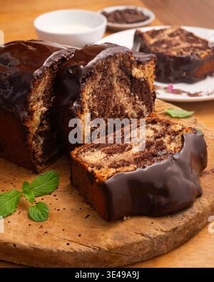Köstlicher Marmor-Schokoladenkuchen mit glänzender Ganache und frischer Minzgarnitur Stockfoto