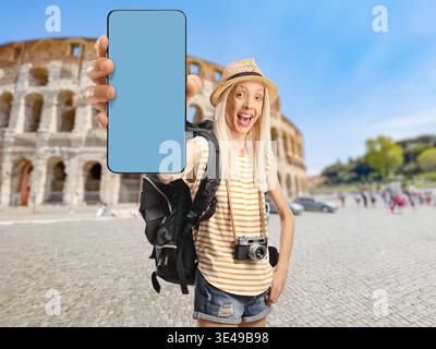 Eine junge Reisende im Kolosseum, die einen leeren Smartphone-Bildschirm hält Stockfoto