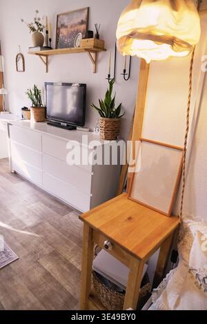 Helles und einladendes Wohnzimmer mit Pflanzen, moderner Einrichtung und gemütlicher Beleuchtung für eine gemütliche Atmosphäre Stockfoto